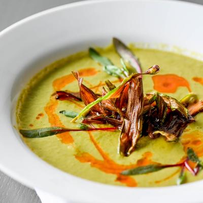 A bowl of creamy green soup garnished with herbs.