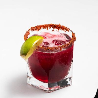 Refreshing Purple Margarita cocktail, with lime wedge and spiced rim.