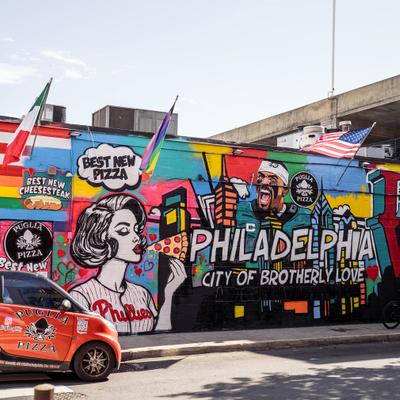 Vibrant Philadelphia graffiti wall art with a delivery car parked on the street.