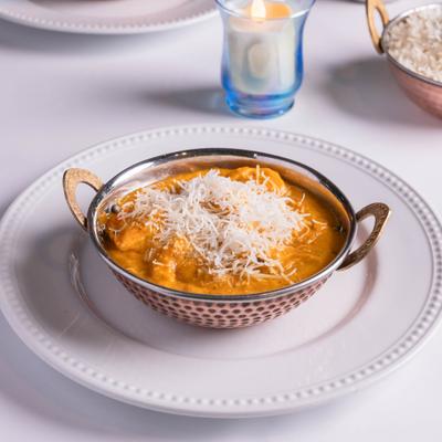 Classic lamb curry  served in a traditional copper bowl on a white table.
