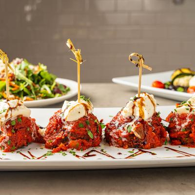 Plated meatballs topped with mozzarella, herbs, and balsamic.