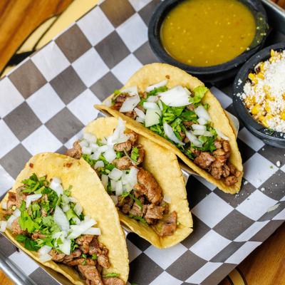 Steak tacos with onion, cilantro, and green salsa.