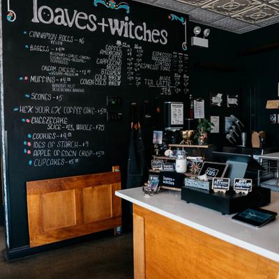 The cafe interior with a counter and a blackboard listing baked goods and beverages.