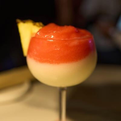 Frozen layered cocktail with pineapple garnish.