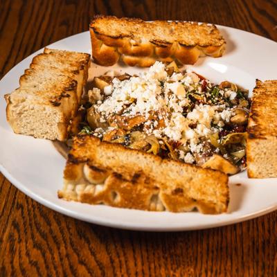 Mediterranean medley dish on a white plate, served with focaccia.