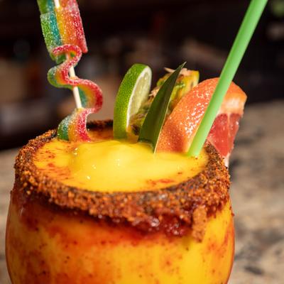 Mango Margarita served in a chili-rimmed glass with various garnishes.