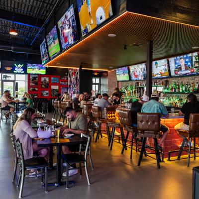 Interior with a mix of counter and table seating and numereus television screens.