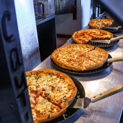 Pizzas with various toppings on the buffet counter.
