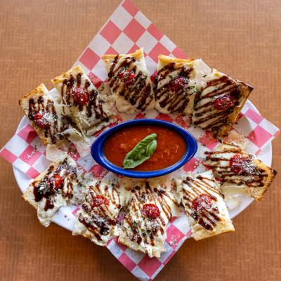 Bruschetta platter with balsamic drizzle and a bowl of marinara sauce.
