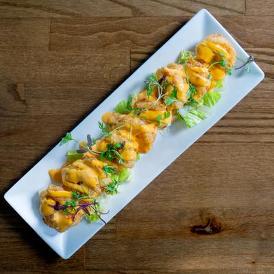 Boom Boom Shrimp wit a spicy creamy sauce served on a  rectangular plate.