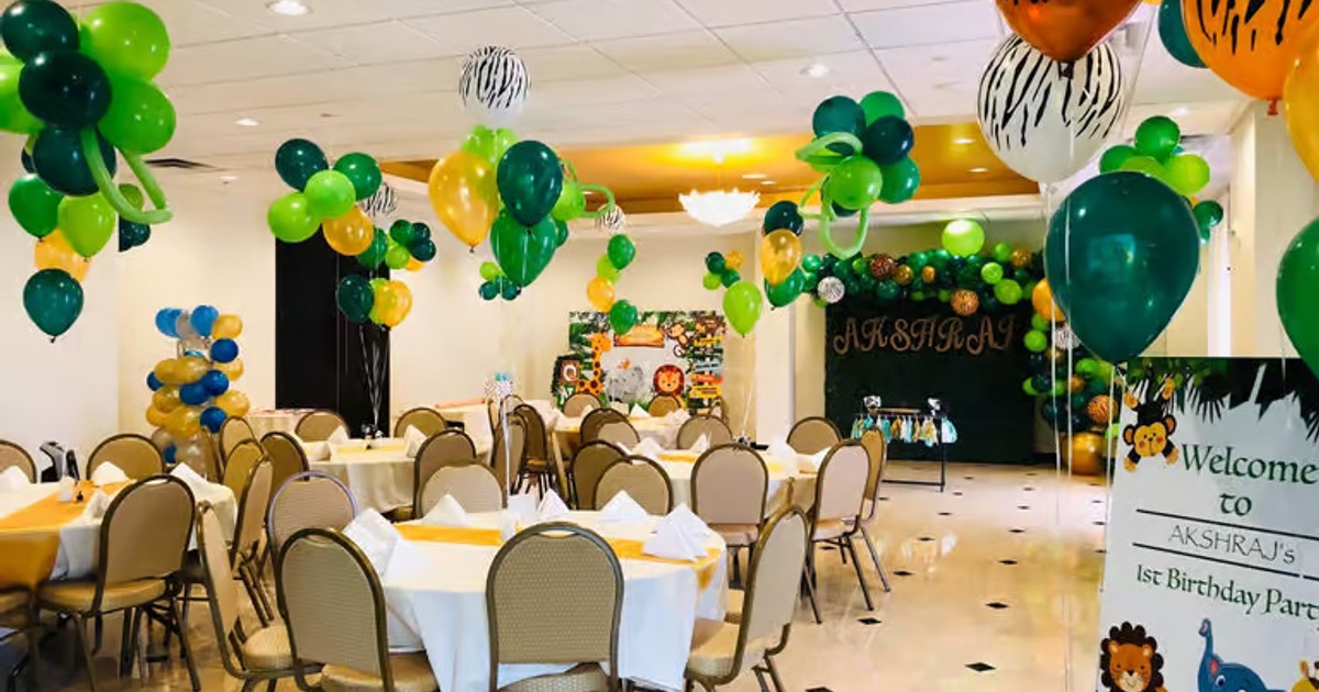 Room decorated for a child's first birthday, featuring multiple round tables and balloons