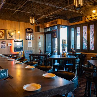 Interior with a long bar counter with stools and several dining tables and chairs.