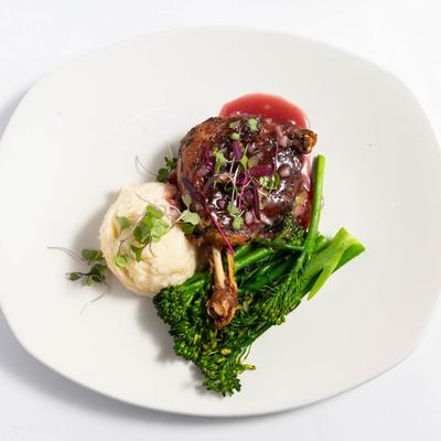Duck leg with mashed potato, broccolini, and micro greens.