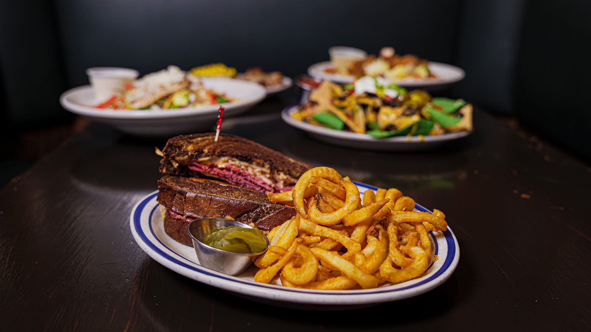 Enjoy a delicious grilled Reuban with a side of curly fries.