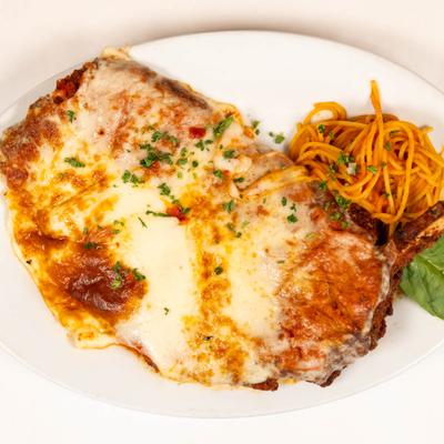 Veal Parmigiana topped with melted cheese and served with spaghetti.