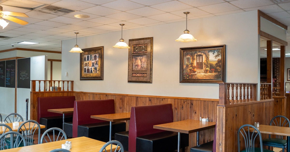 Interior - wooden tables & maroon booth seating, framed paintings on the walls; warm light fixtures.