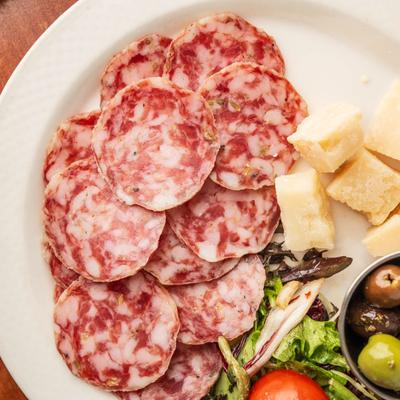 Mixed antipasto with sliced salami cheese and greens.