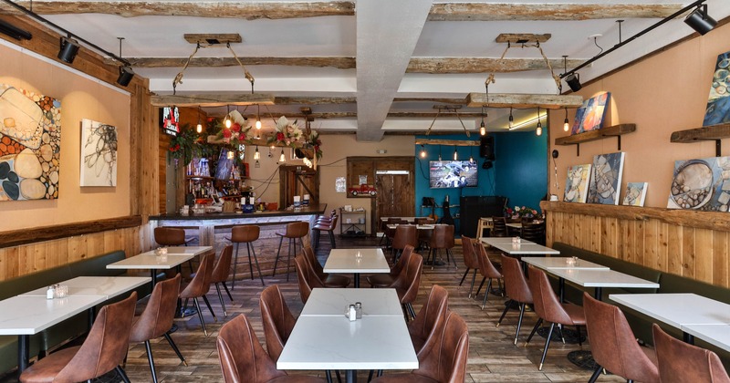 Interior with white tables, brown chairs, a bar, and abstract art on the walls