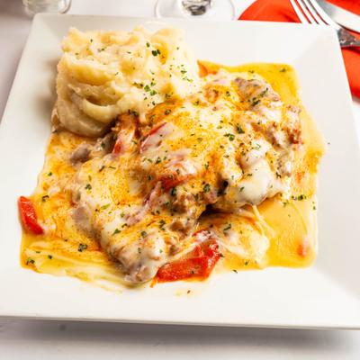 Melted cheese entree with mashed potatoes and sauce on a square plate