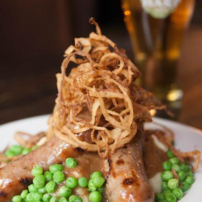 Bangers and mash, with green peas and crispy fried onions.