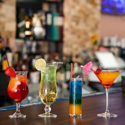 Glasses of assorted cocktail drinks aligned on a bar counter.