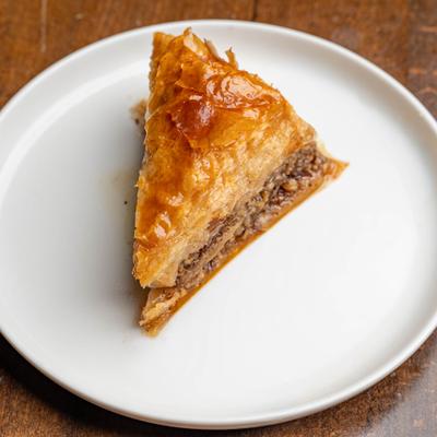 A slice of baklava sits on a white plate.