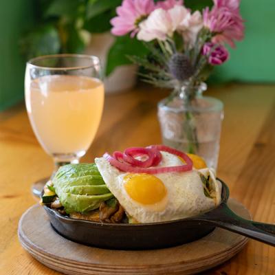 Sunny side up eggs and avocado meal with a beverage.