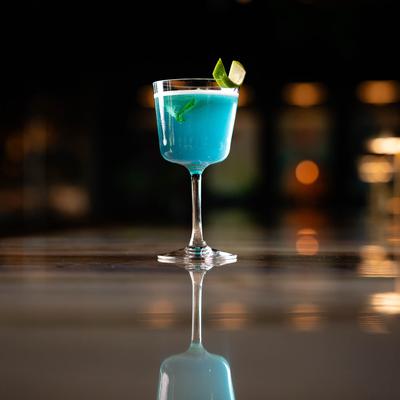 Blue Ocean Water cocktail sits on a reflective surface.