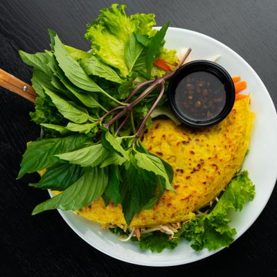 Crispy Vietnamese turmeric pancake with fresh herbs and dipping sauce.