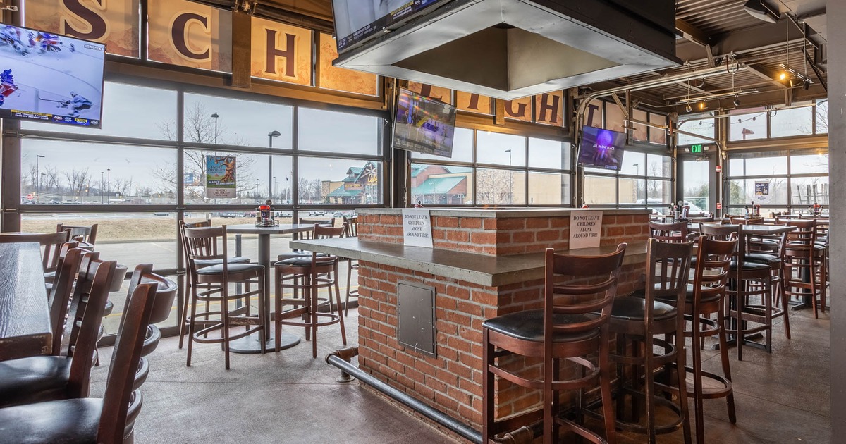 Interior, seating area featuring tables and chairs with a large fire pit in the middle of the room