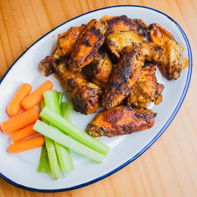 Roasted chicken wings served with carrots and celery sticks.