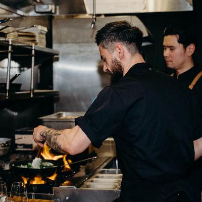 Chefs cooking over flames.