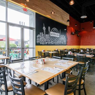Modern restaurant interior with mural wall and wooden tables.