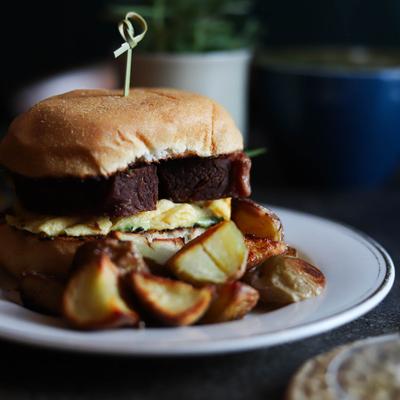 Corned beef sandwich with caramelized onion and egg, served with roasted potatoes.