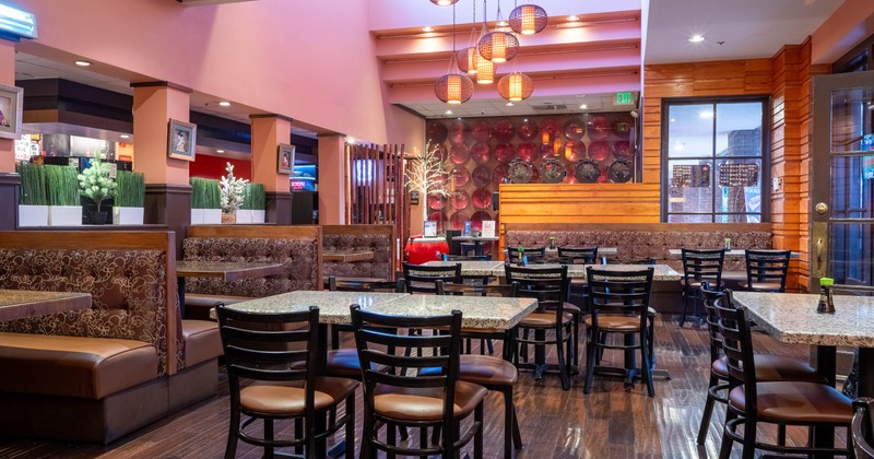Interior with granite tables, wooden chairs and booths under hanging lantern lights