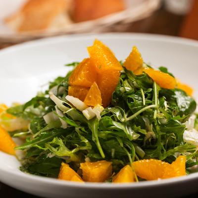 A close-up of a salad with frisee lettuce, fennel, and orange slices.