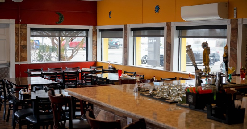 Interior, a bar in front, tables with chairs in the back