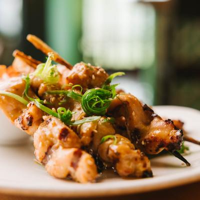 Grilled chicken skewers garnished with green onions.