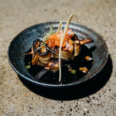 Grilled seafood skewers topped with fresh vegetables and herbs.