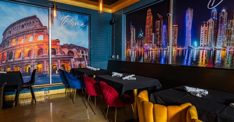 Interior space, lined up tables with black tablecloths and upholstered chairs in different colors