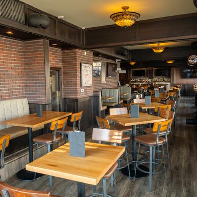 Dining area with wooden tables, chairs and warm lighting.