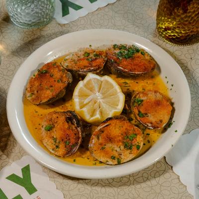 A plate of baked clams with fresh lemon.