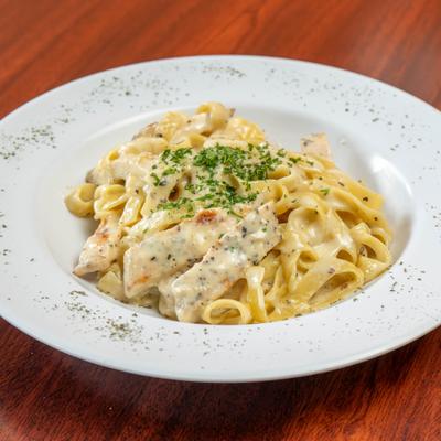 Chicken Fettuccine Alfredo on a white plate topped with herb seasoning.