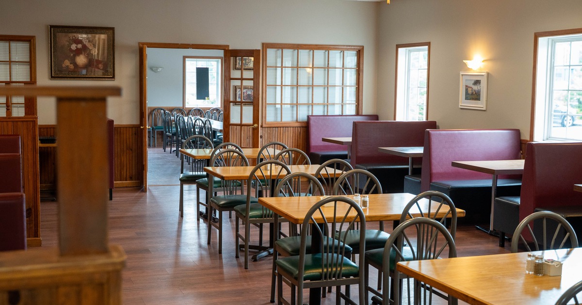 Interior - wooden tables and green chairs, maroon booths and large windows.