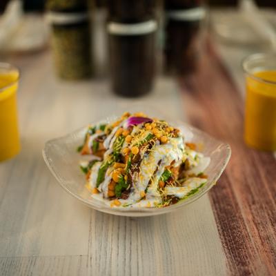 Samosa chaat topped with yogurt, chutneys, and crunchy sev.