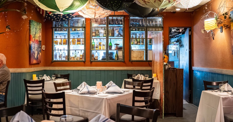 Cozy restaurant interior featuring colorful umbrellas on the ceiling, white tablecloths on tables