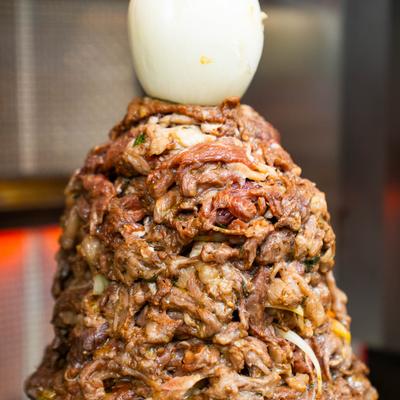 A vertical rotisserie of seasoned pork.