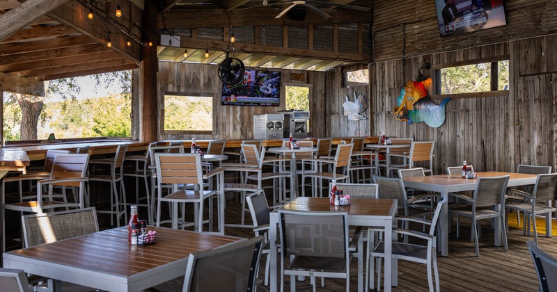 Terrace seating area, tables and chairs, TV screens on the walls