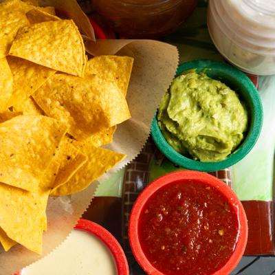 Tortilla chips with cheese dip, guacamole, and salsa.