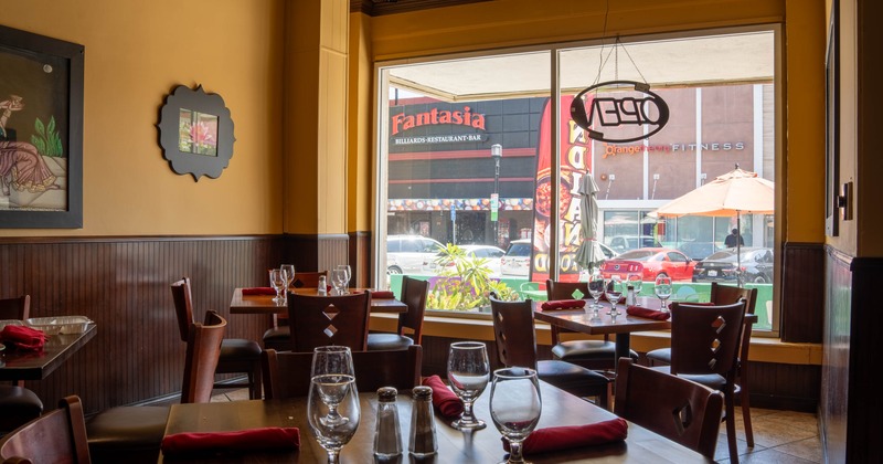 Cozy restaurant interior with wooden tables, red napkins, and wine glasses